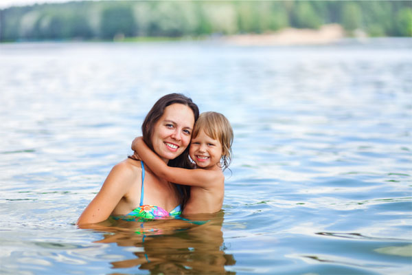Glückliche-Mutter-beim-planschen-mit-Tochter-im-See